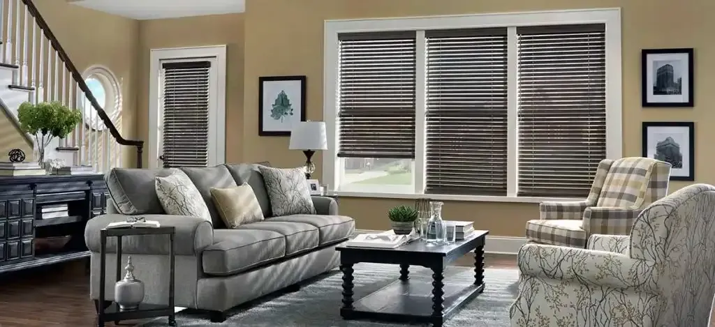 Living room with a gray sofa, patterned chair, coffee table, and wood blinds