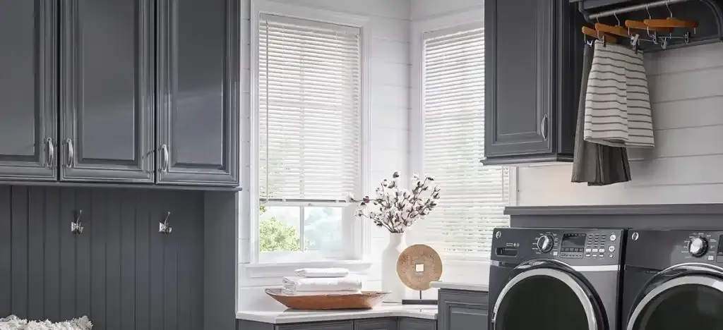 Laundry room with gray cabinets, a window, and a washer and dryer.
