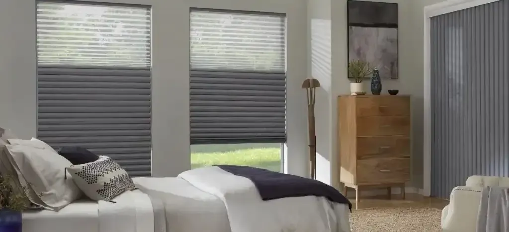 Bedroom with window blinds, a wooden dresser, and a bed with pillows.