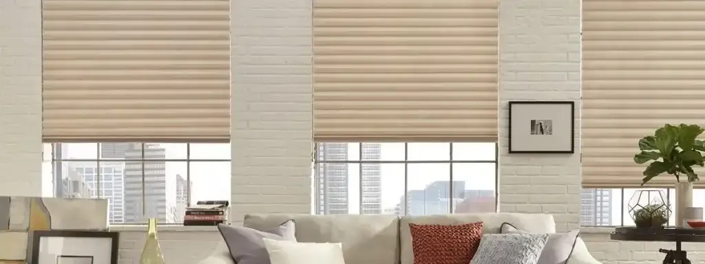 Living room with cream-colored pleated shades, exposed brick walls, and a sofa with pillows, overlooking a cityscape.