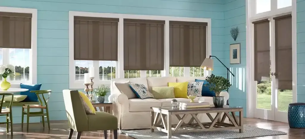 Living room with blue walls, white trim, brown shades, white couch, and light-colored furniture.