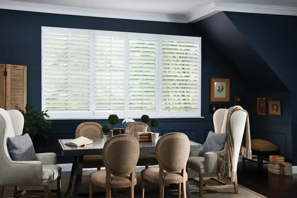 Dining room with navy blue walls, white shutters, and a table with chairs.
