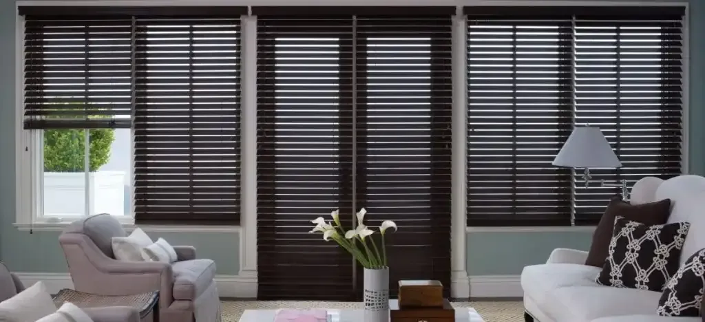 Living room with closed dark wood blinds; white sofas, blue walls, white trim.